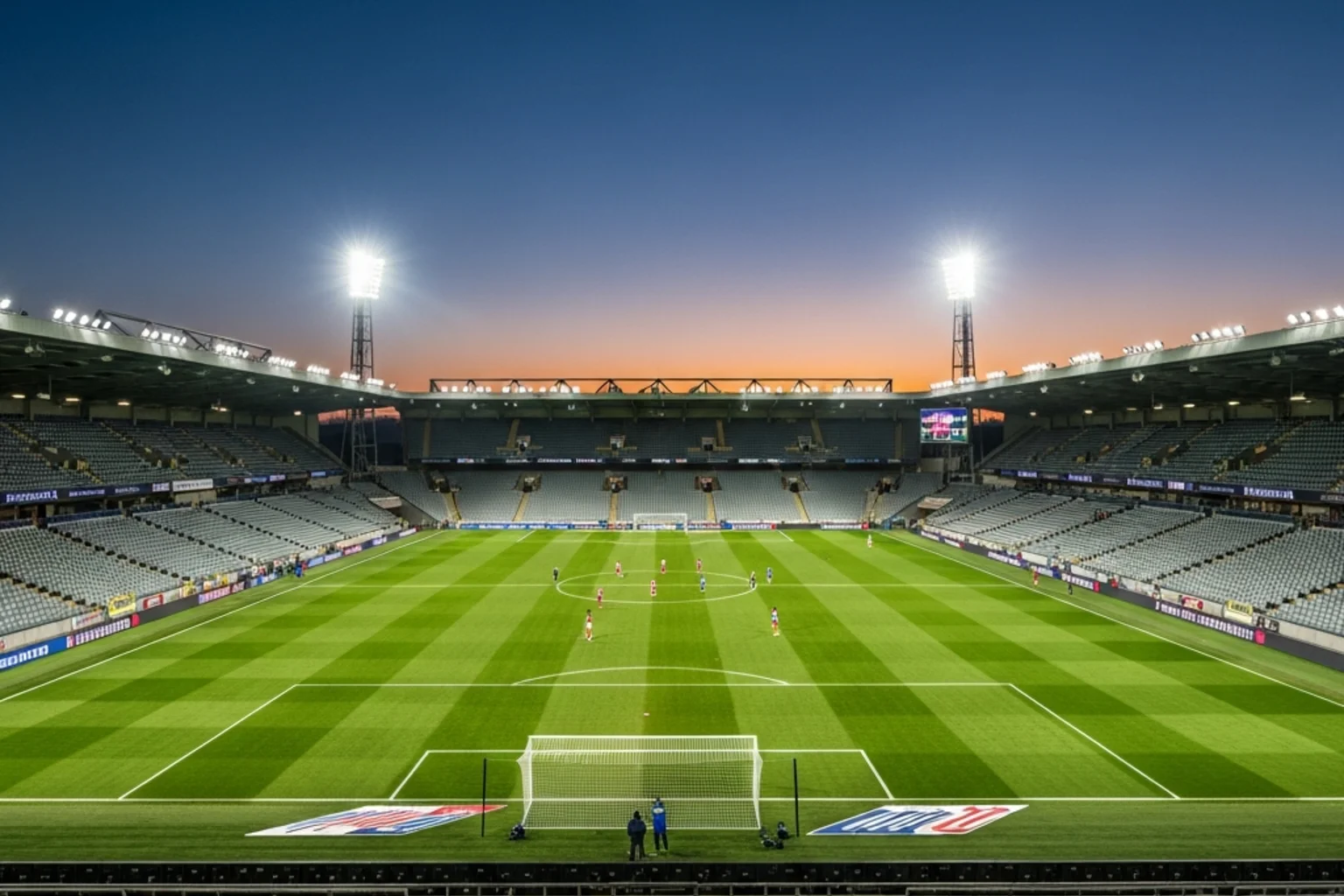 Football stadium under floodlights viewed from the stands at dusk
